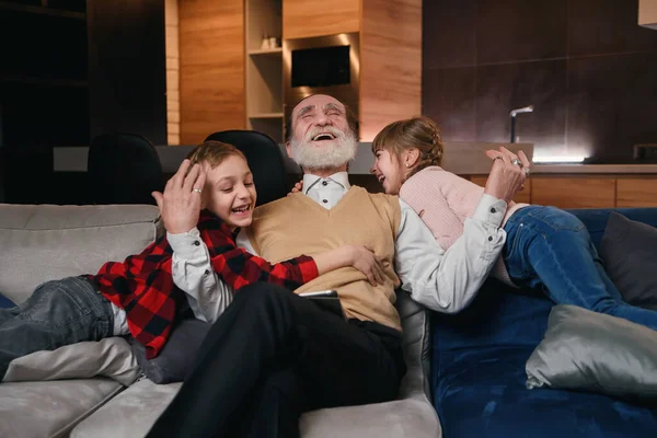 Avô e netinhos se divertindo juntos, gritando e rindo. Desfrutando de lazer com a família passar fim de semana juntos em casa aconchegante . — Fotografia de Stock
