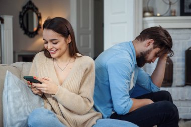 Evde modern bir çift var. Erkek ve kadın akıllı telefonlarla mesajlaşmaya, birbirlerini görmezden gelmeye ve sosyal medyada vakit geçirmeye odaklandılar..