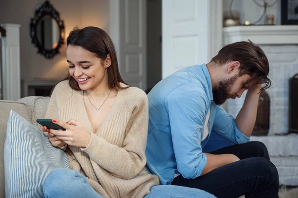 Coppia moderna a casa. Uomo e donna si sono concentrati sulla messaggistica con gli smartphone, ignorandosi e trascorrendo del tempo sui social media . — Foto Stock