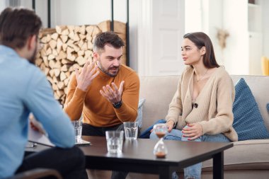 Terapi odasındaki koltukta oturan mutsuz çift.