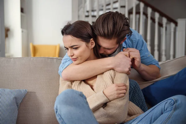 Wait. Worried young man is consoling his girlfriend while touching her arm gently. Woman is holding mobile phone and looking at boyfriend with offence — Stock Photo, Image