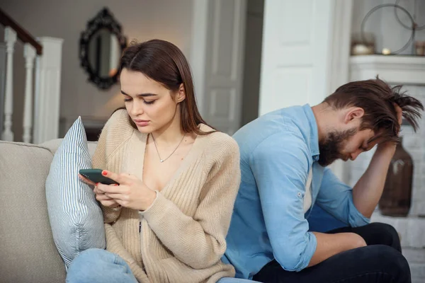 Pasangan modern di rumah. Pria dan wanita berkonsentrasi pada pesan dengan smartphone, mengabaikan satu sama lain dan menghabiskan waktu di media sosial. — Stok Foto