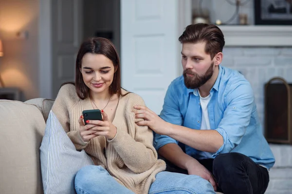 Nowoczesna para w domu. Mężczyzna i kobieta koncentrują się na wysyłaniu wiadomości za pomocą smartfonów, ignorowaniu się nawzajem i spędzaniu czasu w mediach społecznościowych. — Zdjęcie stockowe