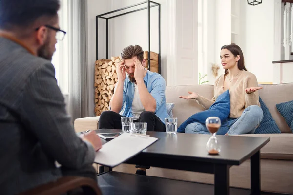 Pareja infeliz discutiendo, teniendo pelea, desacuerdo en la oficina de psicólogos, frustrada familia joven discutiendo problemas de relación con su terapeuta — Foto de Stock