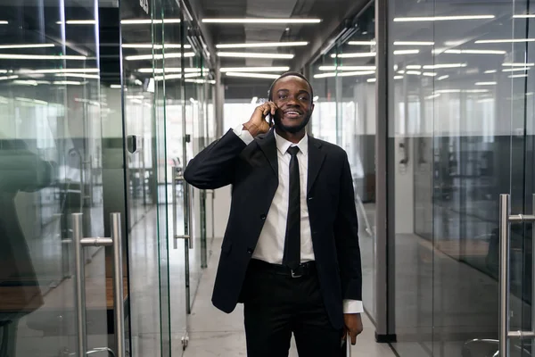 Successful business man have telephone conversation while standing in empty office corridor. Male professional banker in suit talking on mobile phone during work break.