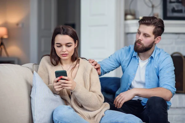 Современная пара дома. Мужчина и женщина сосредоточились на обмене сообщениями со смартфонами, игнорировании друг друга и проведении времени в социальных сетях . — стоковое фото
