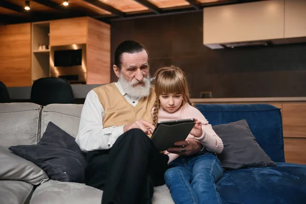 Avô com sua neta usando tablet em casa — Fotografia de Stock