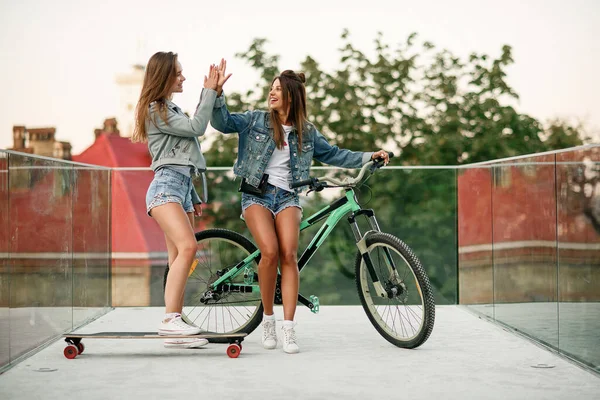 Uma menina na moda dos anos 30 com bicicleta esperando por sua amiga quente em shorts tentadores no deck de observação especialmente equipado — Fotografia de Stock