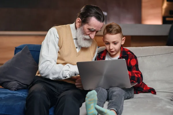 El nieto está enseñando a su abuelo a usar la computadora portátil . — Foto de Stock