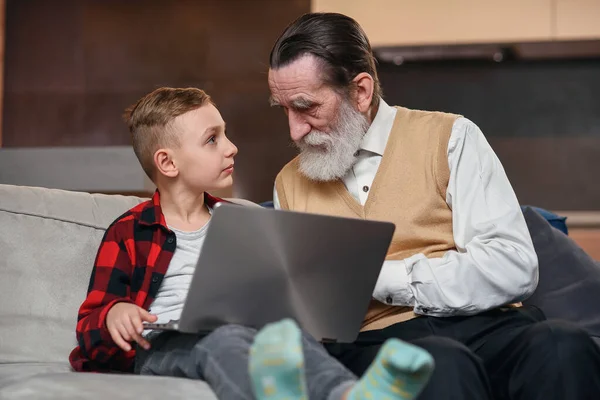 El nieto está enseñando a su abuelo a usar la computadora portátil . — Foto de Stock