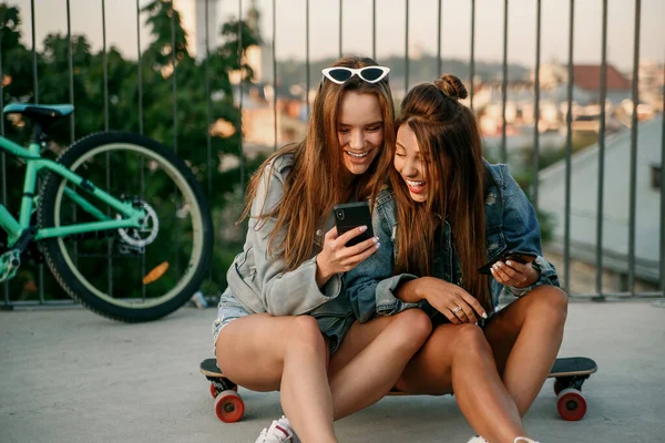 As namoradas usam smartphone enquanto caminham na cidade de manhã. As blogueiras femininas viajam pela Europa. Comunicação moderna tecnologias inteligentes e conceito de amizade . — Fotografia de Stock