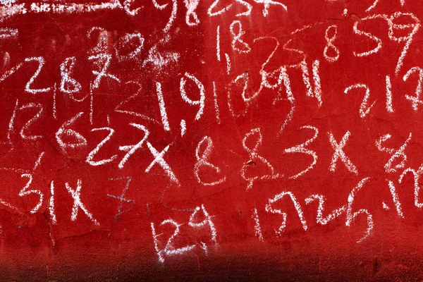 Kırmızı boya üzerinde çocuklar tarafından soyut farklı rakamlar çizilir yıpranmış. Fırça darbeleri.