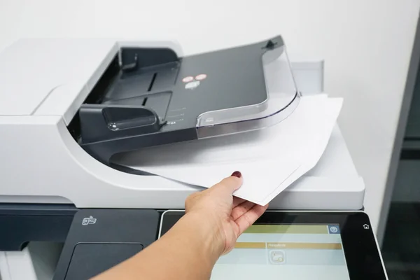 Business woman pull pieces of paper from printer — стоковое фото