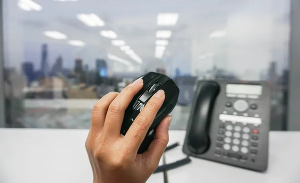 Tenere il mouse del computer in mano con lo sfondo del telefono IP — Foto Stock