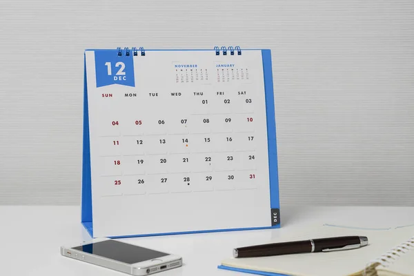 Calendario de diciembre aislado en la mesa con teléfono inteligente y pluma —  Fotos de Stock