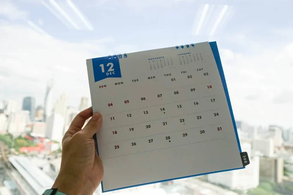 女性は12月のカレンダーを左手に持っている — ストック写真
