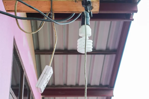 Спиральная лампочка и вилка висят на крыше дома — стоковое фото