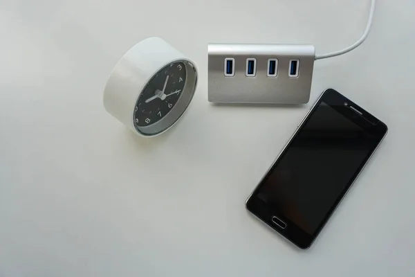 Smartphone isolé avec hub USB et horloge moderne sur bureau — Photo