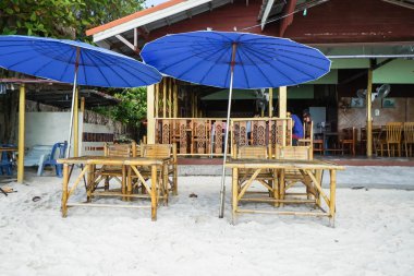 tatil ve dinlenme kavramı - bambu masa ve sandalye ile mavi şemsiye plajda