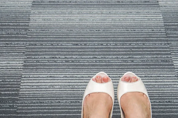 Närbild av vita kvinnor högklackade skor på office mattan — Stockfoto