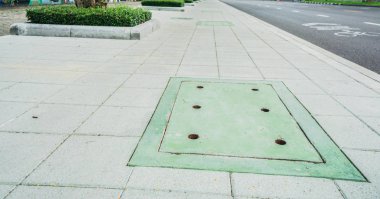 Beton patika üzerinde yeşil kanalizasyon kapağı