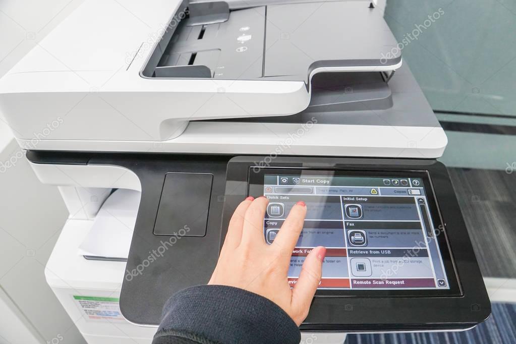 business woman with left hand press on printer touch screen for copying documents