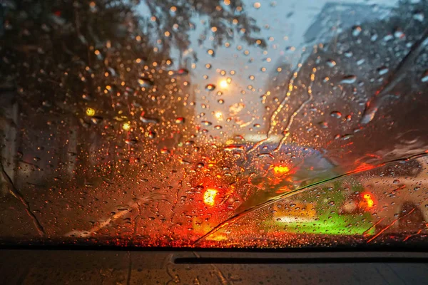 Regentropfen mit Rücklicht Bokeh in der Nacht auf Auto Windschutzscheibe bei starkem Sturm — Stockfoto
