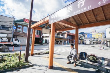 Tokyo, Japonya'da 5 Ocak 2017 alınan Chuzenji onsen için otobüs durağında kameralı adam