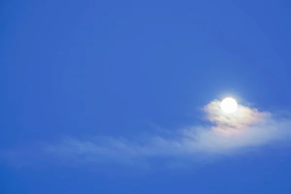 bright full moon with clouds in deep blue sky in winter