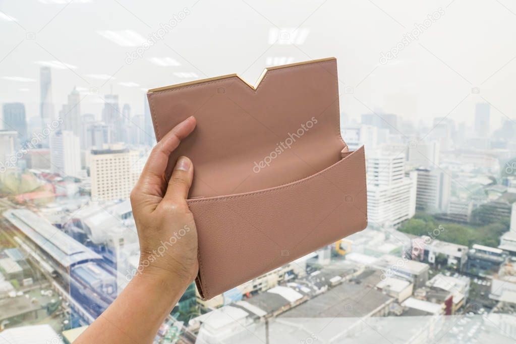 close up woman hand holds cute beige leather wallet for money with left hand