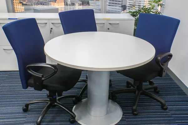 close up white round table with blue chairs for office meeting