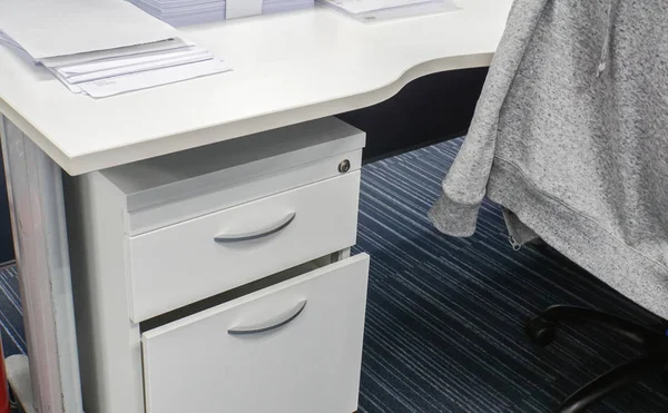 close up desk drawer and office desk with jacket on chair