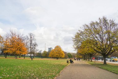 insanlar ahşap bankta oturup sonbaharda Hyde Park Londra'da yürümek