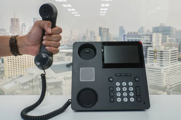 close up businessman hold IP phone handset to call for conference meeting