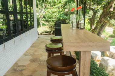 Çiçek vazosu ve ev bahçesinde sandalyeleri olan uzun tahta bir masa.