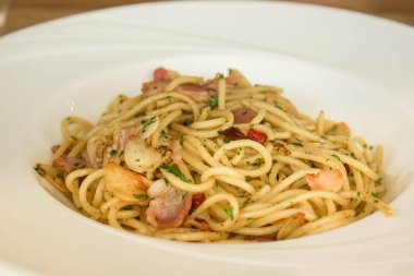 Müşterilere servis yapmak için beyaz tabakta baharatlı deniz ürünleri spagettisi.