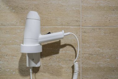 Beyaz saç kurutma makinesini kapatın ve banyo fayans duvarına asın.