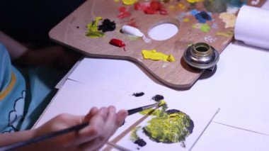 Küçük çocuk beş yılın ilk resmini çizer. Çocuk boya tuval üzerine yağlı boya ile. Küçük çocuk berabere Minion sarı boya kullanarak.