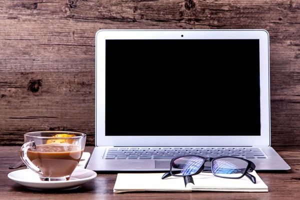 Компьютер, очки, ноутбук и чай на рабочем столе — стоковое фото
