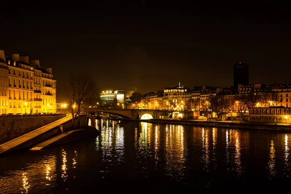 Night urban scene of a calm river crossing a big city — Stock Photo, Image