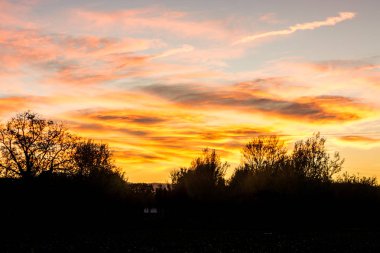 Bir tepenin arkasında bulutlu gökyüzü günbatımı
