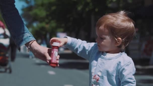 Little girl blows soap bubbles — Stockvideo