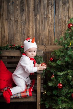 Bir çocuk Kostüm giymiş bir kardan adam, yılbaşı ağacı.
