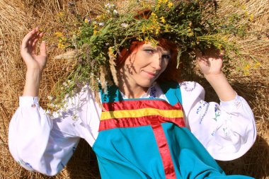 Samanlık üzerinde Rus ulusal elbiseli kızıl saçlı kız.