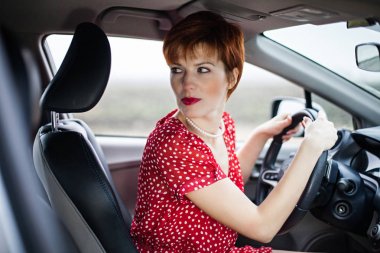 Kızıl saçlı kız bir arabanın direksiyonuna.