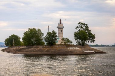Deniz feneri. Adası denizin içinde. Yaz manzara. Ufuk. Mavi gökyüzü. Yeşil ağaçlar