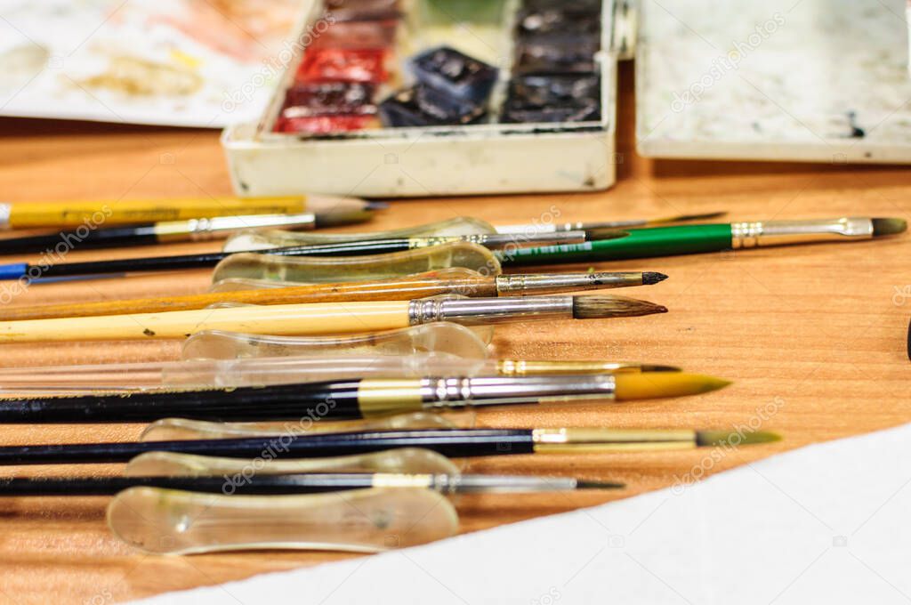 Paintbrushes and watercolors on wooden table