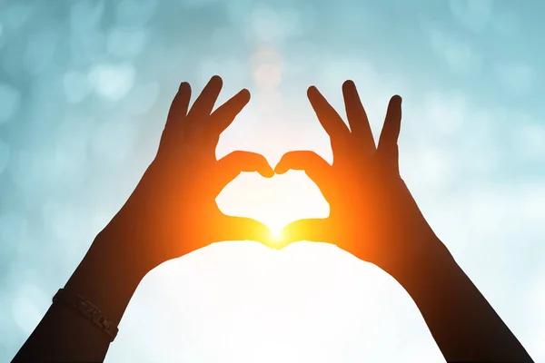Mãos sob uma forma de coração silhueta .heart com a mão sob o pôr do sol  . — Fotografia de Stock