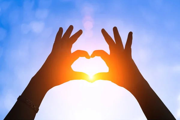 Ruce pod obrazcem ve tvaru srdce .heart silueta s rukou pod západ slunce . — Stock fotografie