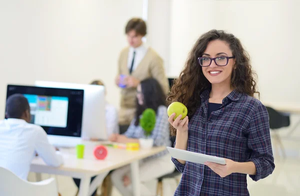 Jovem mulher comer uma maçã no escritório — Fotografia de Stock